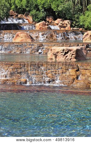 The spectacular cascade fountain. Multistage stone fountain surrounded by tropical vegetation and palm trees