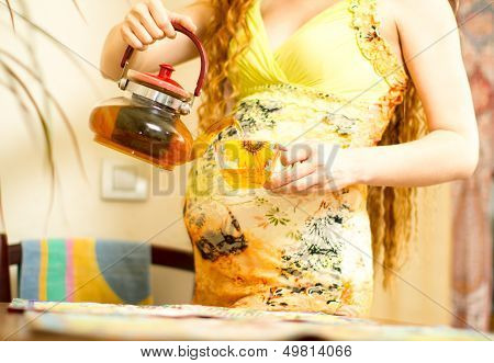 Pregnant Woman  With A Cap Of Tea On Kitchen. The Concept Of Drinking And A Healthy Lifestyle