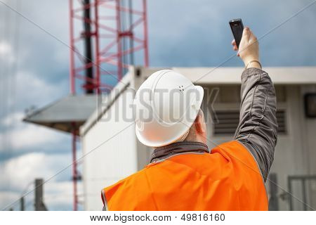 Engineer with the cell phone near to gsm tower