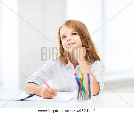 education and school concept - little student girl drawing at school