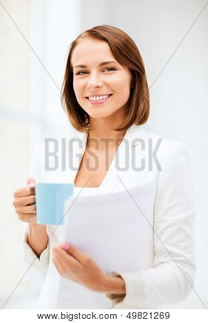 business concept - businesswoman with cup of coffee and folders in office