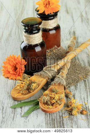 Medicine bottles and calendula flowers on wooden background