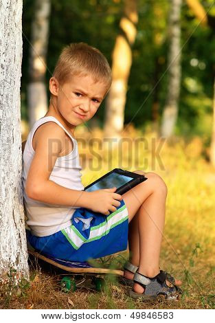 Boy Child Playing With Tablet Pc Sitting On Skateboard Outdoor With Forest On Background Game Depend