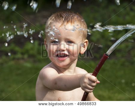 Toddler Playing In The Garden With A Water Hose