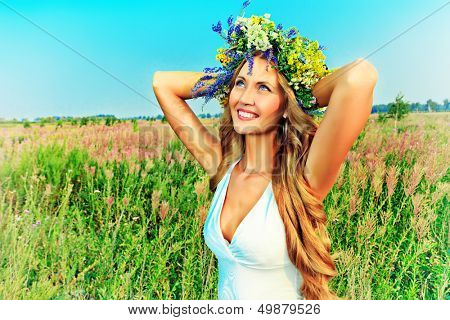 Portræt af en romantisk smilende ung kvinde i en tudorroser af blomster udendørs.