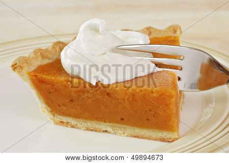 Tranche de tarte à la citrouille fraîchement cuits au four avec crème fouettée et une fourchette.  Closeup avec dof peu profond.