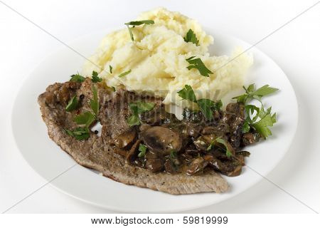 Fried and peppered escalope of veal served with mashed potatoes and a creamy sauteed mushroom sauce