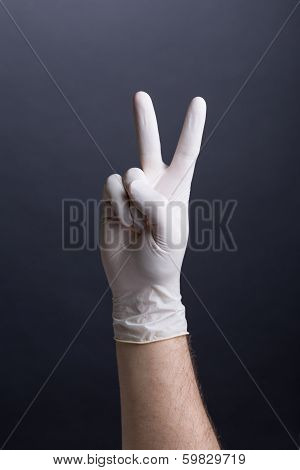 Male hand in latex glove - victory gesture, v-sign