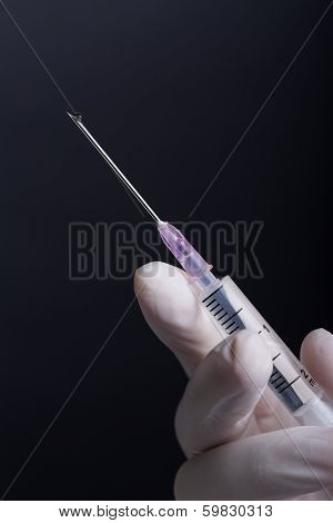 Hand in latex gloves holding syringe