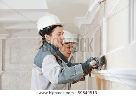 Plasterer at indoor wall renovation stucco decoration with float and plaster