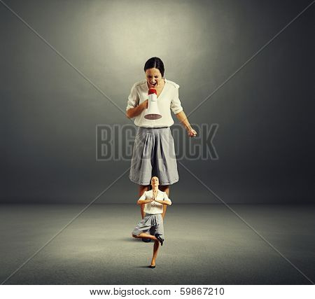 concept photo of self reproach. angry big woman screaming at small yoga woman