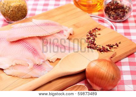 Raw fish tilapia on cutting board and spices