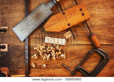 Wood working. Saw, clamps and wood shavings on a work desk under incandescent light. 
