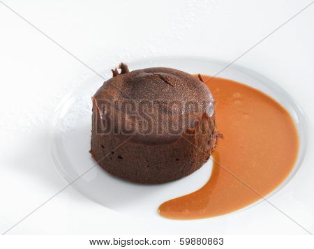 Delicious chocolate fondant with caramel sauce served on a white round plate. Isolated on white.