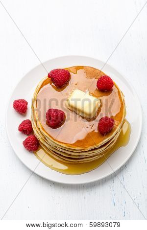 Big Pile of American  Pancakes with Raspberries, Melted Butter and Maple Syrup