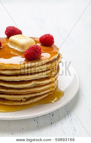 Big Pile of American  Pancakes with Raspberries, Melted Butter and Maple Syrup