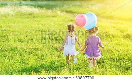 Happy Girls Twin Sisters  With Balloons In Summer Field On Nature