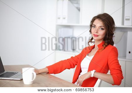 Attractive woman sitting at desk in office, working with laptop computer