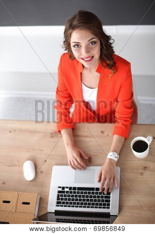 Attractive woman sitting at desk in office, working with laptop computer