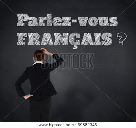 Young businesswoman standing and thinking against blackboard, Do you speak French?