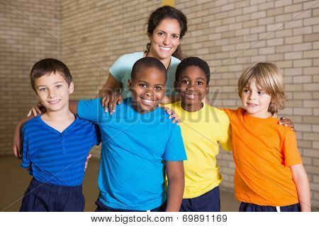 Cute pupils smiling at camera with PE teacher at the elementary school