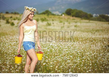 Portrait of beautiful young woman with berries in the field