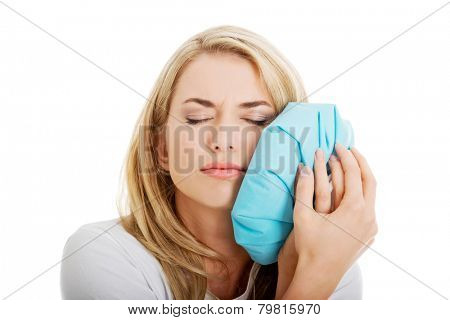Woman heaving tooth ache, holding ice bag