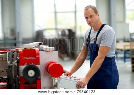 young worker in factory using machine