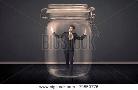 Businessman trapped into a glass jar concept on background