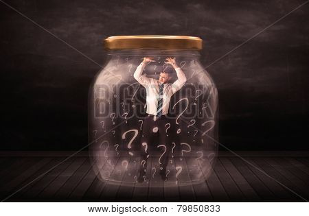 Businessman locked into a jar with question marks concept on background