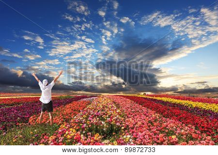 Enthusiastic tourists threw up his hands. Cloudy and windy spring day. Bright festive red, pink and yellow  blooming field of buttercups