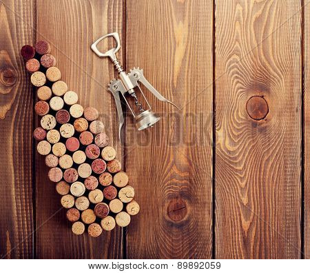 Wine bottle shaped corks and corkscrew over rustic wooden table background. View from above with copy space