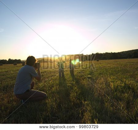 photographer taking pictures of children on a sloping meadow                    