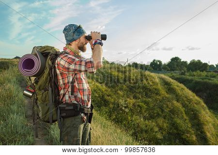 Young caucasian man with backpack standing on the top of hill