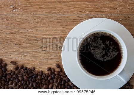 Cup Of Black Coffee And Coffee Beans On Wooden Background.