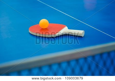 Pingpong Racket And Ball And Net On A Blue Pingpong Table Vertical