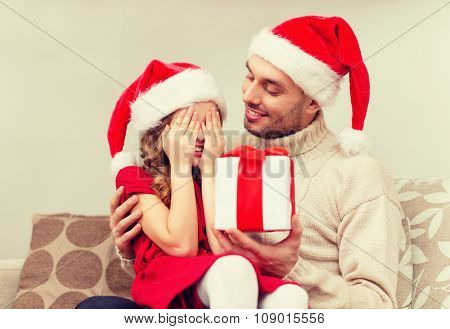 family, christmas, x-mas, happiness and people concept - smiling daughter with closed eyes waiting for a present from fathe