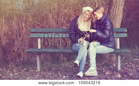 Young woman sitting on bench with her best friend
