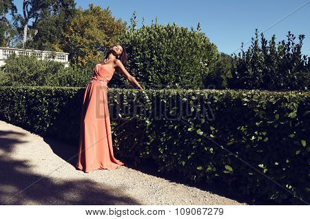 beautiful  girl in coral dress posing in park