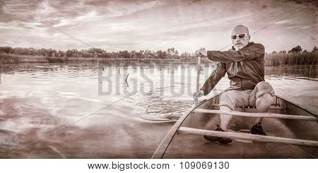 senior paddler enjoying paddling a canoe on a calm lake at sunset, a grunge texture finish in sepia tone