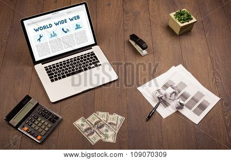 Laptop computer on wooden desk with office suplies