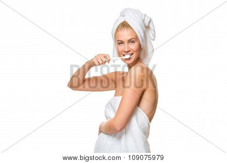 Young attractive woman blue eyes in towel brushing her teeth