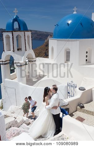 A Couple Of Newlywed’s Tourists In Front Of Church With The View Of Santorini Island, In Greece. Tou