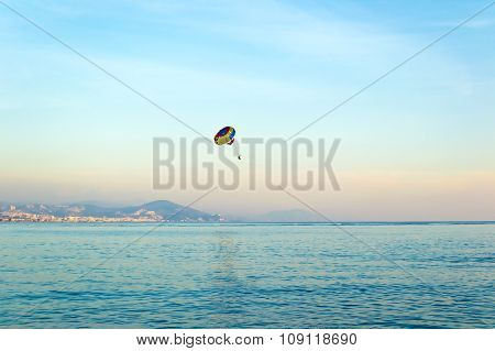 People parasailing over the sea at sunset