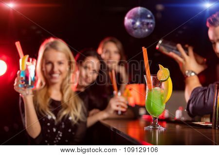 Young friends drinking cocktails together at night bar party. Focus on cocktail drink