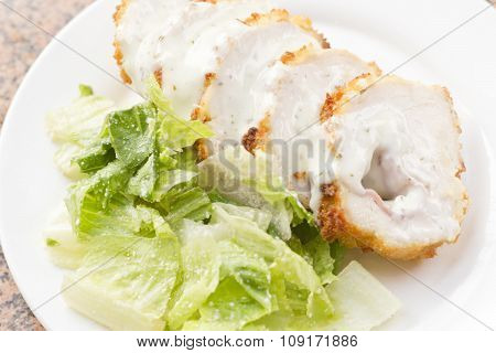Sliced chicken cordon bleu with creamy sauce and romane leaf salad