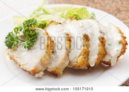 Sliced chicken cordon bleu with creamy sauce and romane leaf salad