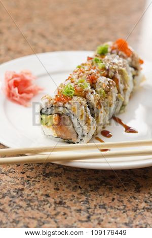 Fancy Philadelphia sushi roll topped with roe sushi sauce and chopped scallions