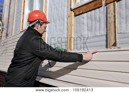 A Worker Installs Panels Beige Siding On The Facade