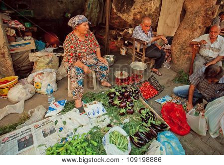 Elderly Woman Sells Eggplant, Peppers And Tomatoes On Rustic Street Market